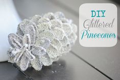 a close up of a ring on a table with text overlay that reads diy glittered pinecones