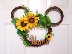 a mickey mouse wreath with sunflowers and greenery hanging on the front door