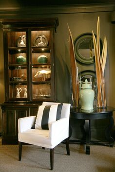 a living room filled with furniture next to a wall mounted china cabinet and vases