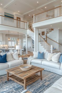 a living room with white couches and blue pillows on the floor in front of stairs