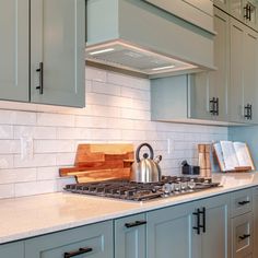 a kitchen with gray cabinets and white counter tops