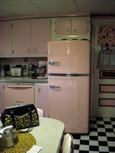 a pink refrigerator freezer sitting inside of a kitchen next to a checkered floor