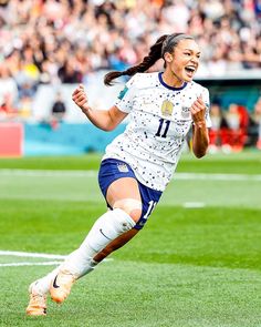 a female soccer player is running on the field with her mouth open and eyes closed