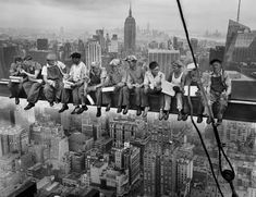 several men sitting on the edge of a high rise