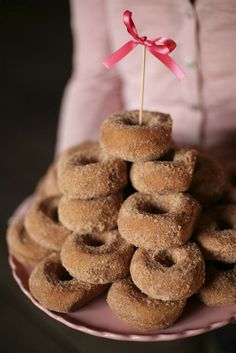 a pink plate topped with donuts covered in powdered sugar and a red ribbon