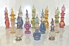 an assortment of colorful glass candlesticks sitting on a white counter top next to each other