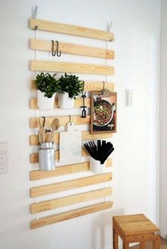 a wall mounted shelf with potted plants and utensils hanging on it's sides