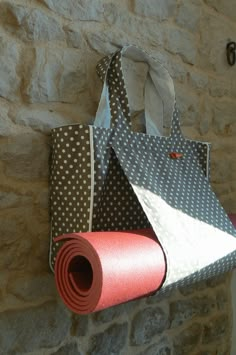 a bag hanging from the side of a stone wall next to a rolled up yoga mat