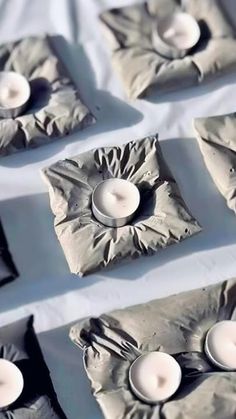 some white candles sitting on top of small trays