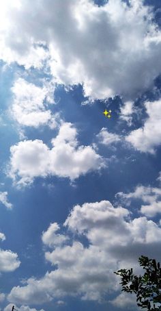 an airplane is flying high in the sky with some clouds behind it and trees below