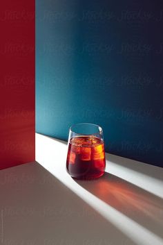 a glass filled with liquid sitting on top of a table next to a red and blue wall