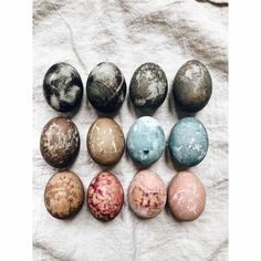 nine different colored eggs sitting on top of a white cloth