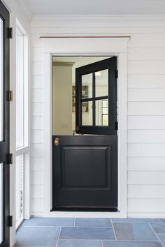 a black door is open on a white house with blue tile flooring and walls