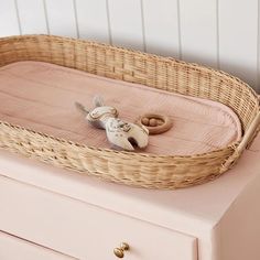 a wicker basket sitting on top of a dresser next to a baby's pacifier