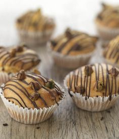 chocolate chip muffins with drizzled and nuts on top sitting on a wooden table