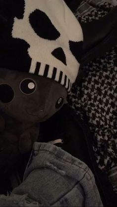 a stuffed animal wearing a knitted skull hat on top of some jeans and sweaters