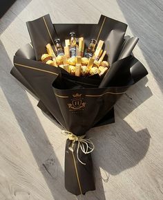 a bouquet of chocolates wrapped in black paper and tied with gold ribbon on the floor