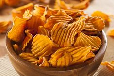 a wooden bowl filled with potato chips on top of a table