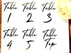 the table numbers are written on a piece of paper with a rose next to it