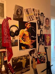 a wall covered in posters and pictures next to a window with a guitar on it