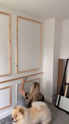 a woman is painting the wall in her living room with white paint and wood trim