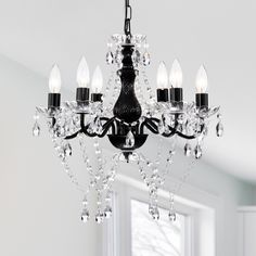 a black chandelier with crystal drops hanging from it's centerpiece in a white room