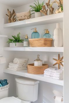 a white bathroom with shelves filled with towels and other items on top of the shelves