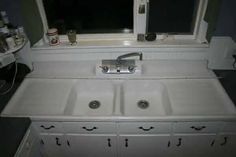 a white sink sitting under a window next to a counter with two faucets