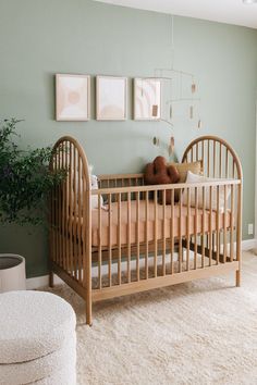 a baby's crib in the corner of a room with pictures on the wall