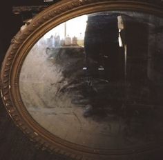 the reflection of a person standing in front of a round mirror on a wooden floor