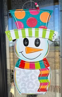 a colorful snowman is hanging on the front glass door to show it's bright colors