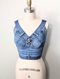 This handmade corset is crafted from upcycled Lucky Brand jeans. Designed to complement your curves, the tailored silhouette provides a flattering fit. With a lace-up back closure and adjustable shoulder straps, this corset offers a customizable fit for your body shape. The removable modesty panel behind the lacing allows you to choose between a more modest look or a hint of skin. Ideal for festivals, parties, or casual gatherings, pair this corset with jeans or a floral skirt for a stylish, bohemian look. Size chart: Adjustable, fits sizes S/M Bust: 34.5" to 37.5" (88cm-95cm) Waist: 26.5" to 29" (67cm-74cm) Care: Hand wash in room temperature water. Do not put in the dryer. Thank you for considering my handmade product! Feel free to contact me with any questions or special requests. All m Fitted Dark Wash Recycled Denim Top, Fitted Upcycled Jeans In Recycled Denim, Upcycled Fitted Jeans In Recycled Denim, Fitted Medium Wash Upcycled Jeans, Corset Unique, Corset With Jeans, Denim Bralette, Jeans Corset, Handmade Corset