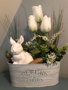 a white rabbit sitting in a basket filled with flowers