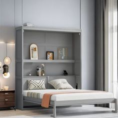 a bed sitting in front of a window next to a wall mounted book shelf filled with books