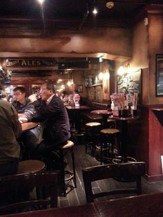 three men sitting at tables in a bar