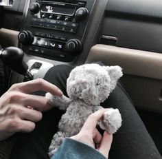 a person holding a teddy bear in their lap while sitting in the driver's seat