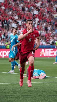 a soccer player is running with the ball in his hand while other players look on