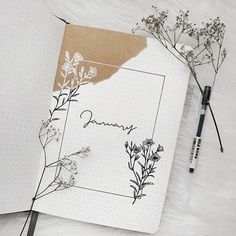 an open notebook sitting on top of a white blanket next to a pen and flowers