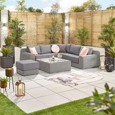 an outdoor living area with grey furniture and plants