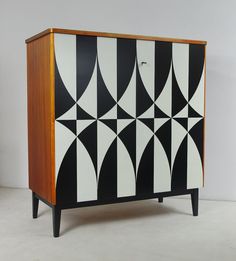 a black and white cabinet with geometric designs on the front, sitting against a wall