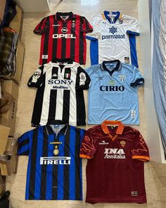 five different soccer jerseys are laying on the floor next to each other, all in different colors and sizes