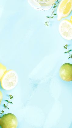 lemons and limeade on a blue background with green leaves around the edges, top view