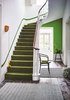 a staircase with green carpet and white railing