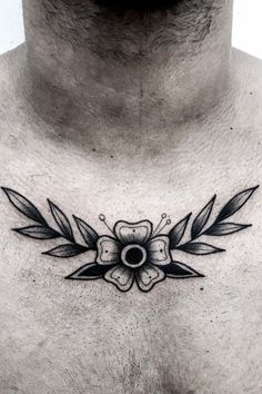 a man's chest with a flower and leaves tattoo on his chest, in black ink