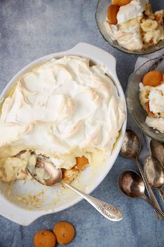 two bowls filled with dessert and spoons next to each other on a blue table cloth