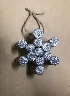 a snowflake ornament hanging from a string on top of a table