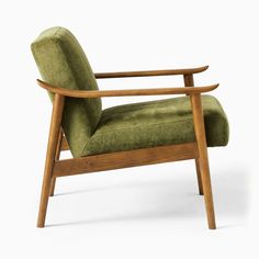 a green chair sitting on top of a white floor next to a wooden armrest