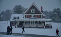 people walking in front of a large red and white house on a snowy winter day