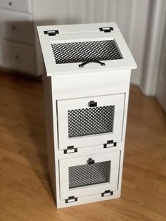 a small white cabinet with drawers on the bottom and one drawer open, sitting on a hard wood floor