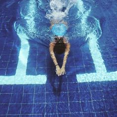 a person swimming in a pool with blue tiles